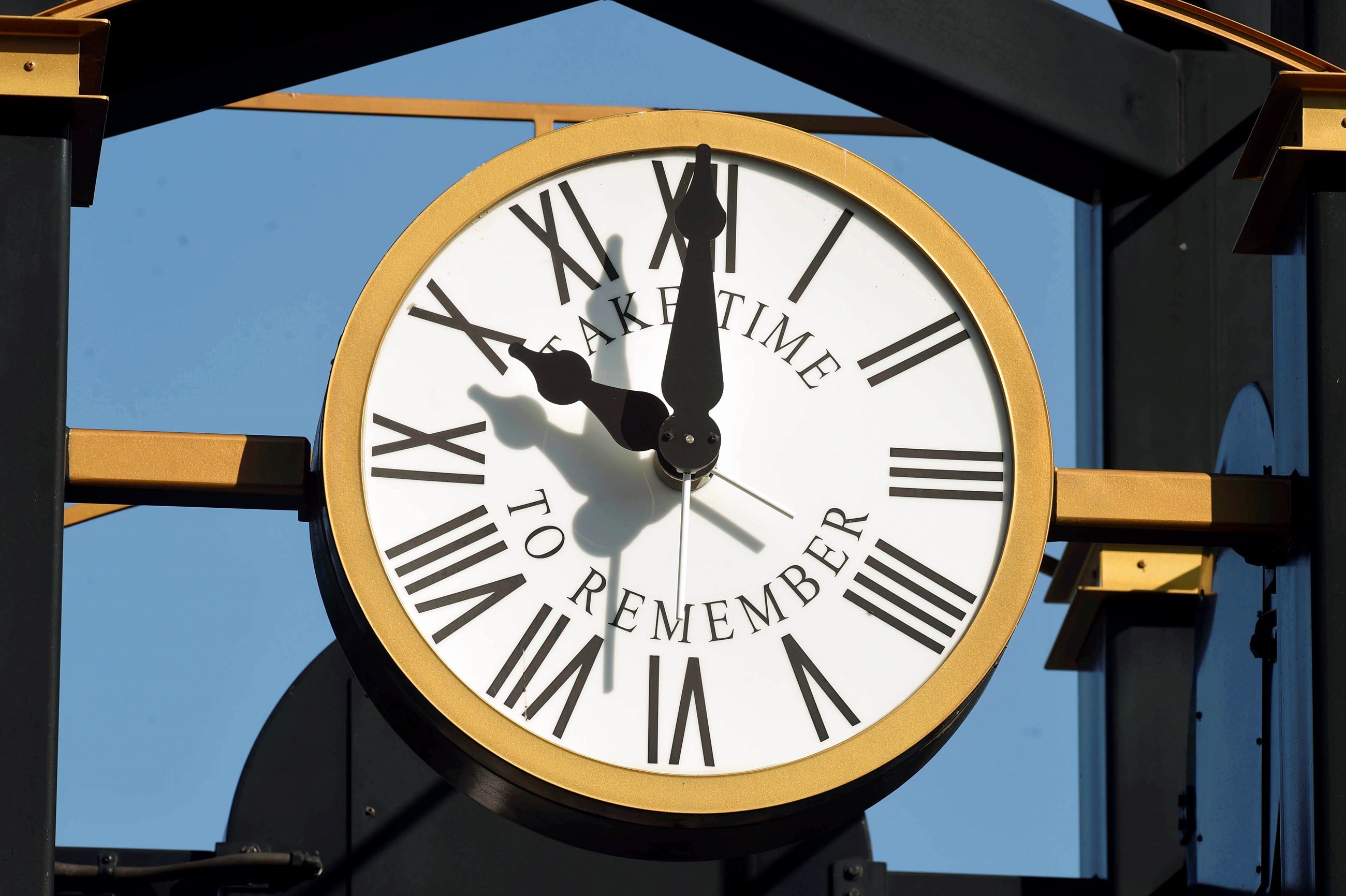 clocktower_8763 Gold clock with white face and large black roman numerals and hands at 10 and 12.