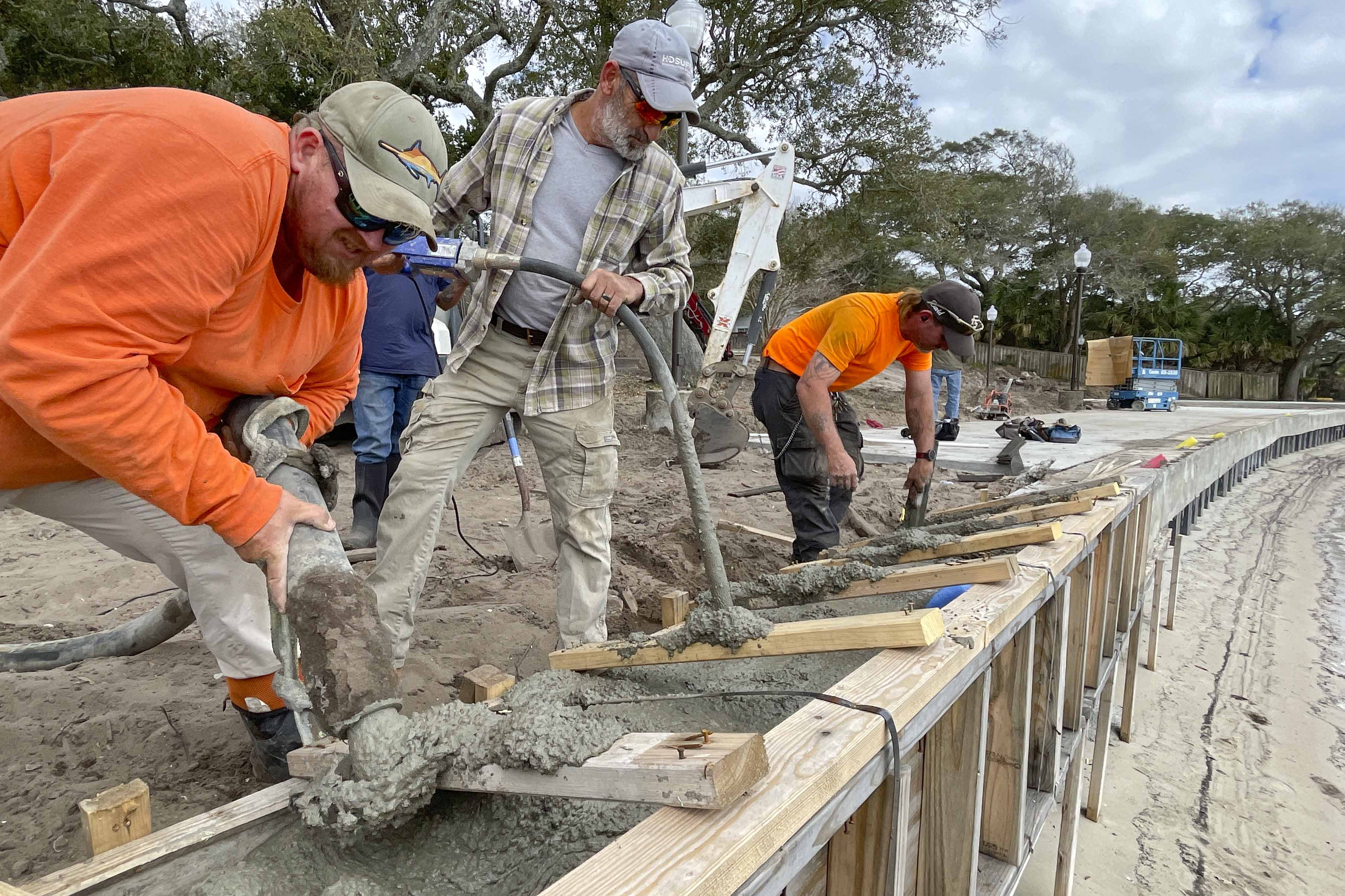 Workers pour and finish concrete for a seawall at the Fort Walton Beach Landing Park..